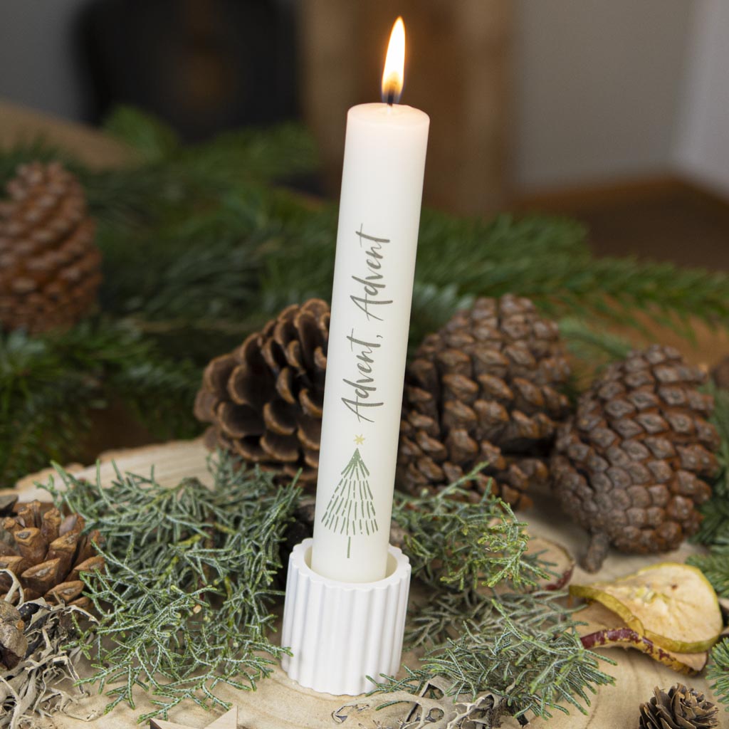 Stabkerze Advent in Creme mit Tannenbaum-Motiv im geriffelten Stabkerzenhalter, winterlich dekoriert