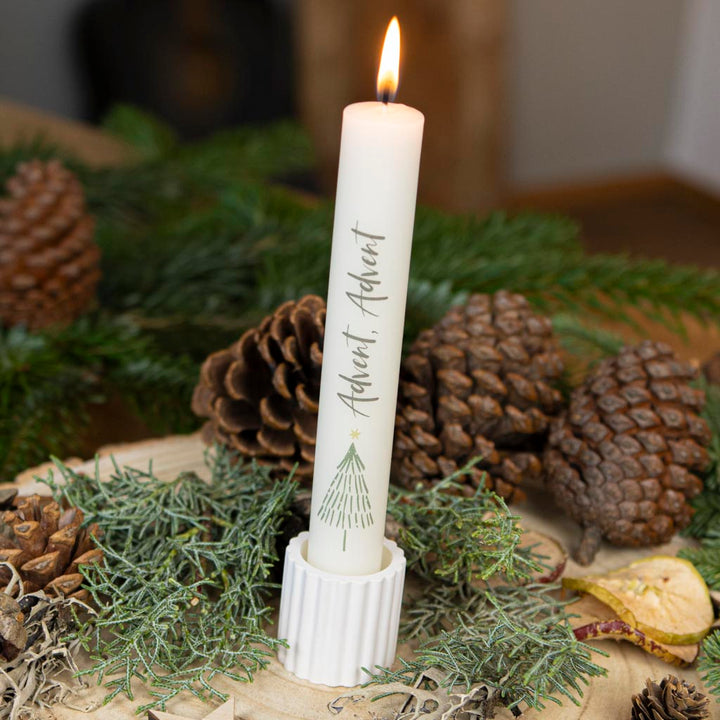 Stabkerze Advent in Creme mit Tannenbaum-Motiv im geriffelten Stabkerzenhalter, winterlich dekoriert