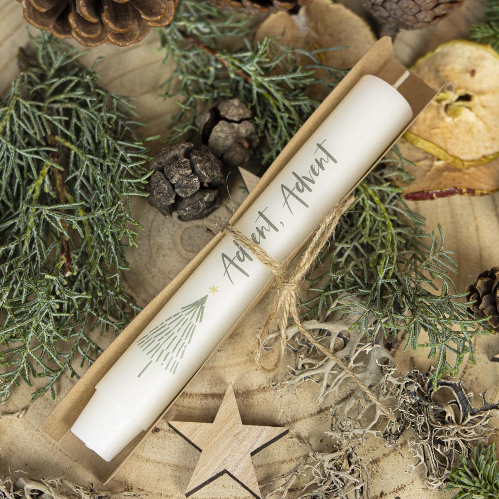 Cremefarbene Stabkerze Advent neben einer Geschenkverpackung aus Karton in winterlicher Dekoration