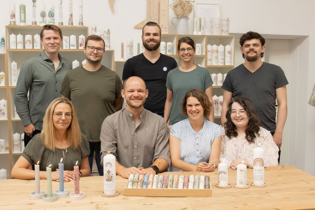 Das Kerzenonkel Team steht zusammen vor einem Regal mit verschiedenen individuellen Kerzen
