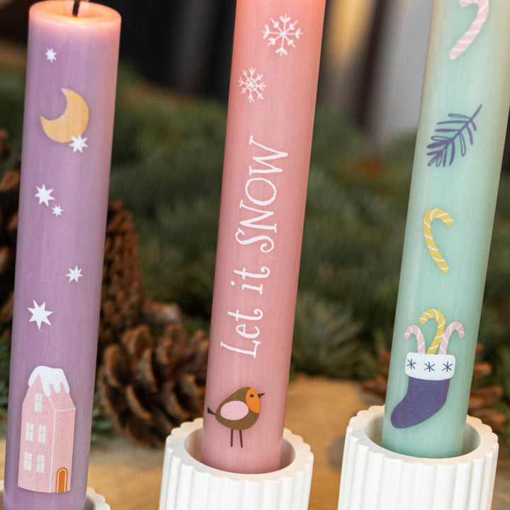 Bunte Stabkerzen mit winterlichen Motiven wie Haus, Sternen und Mond