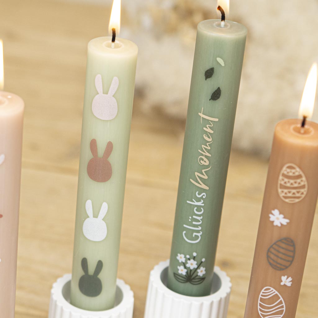Vier bunte Stabkerzen für den Frühling auf dem Ostertisch