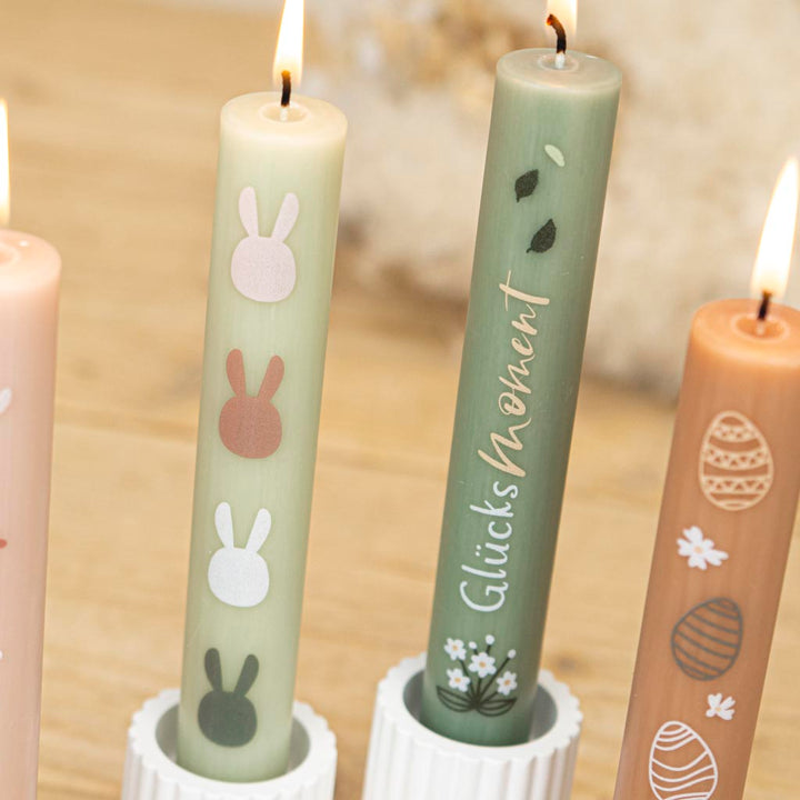 Vier bunte Stabkerzen für den Frühling auf dem Ostertisch