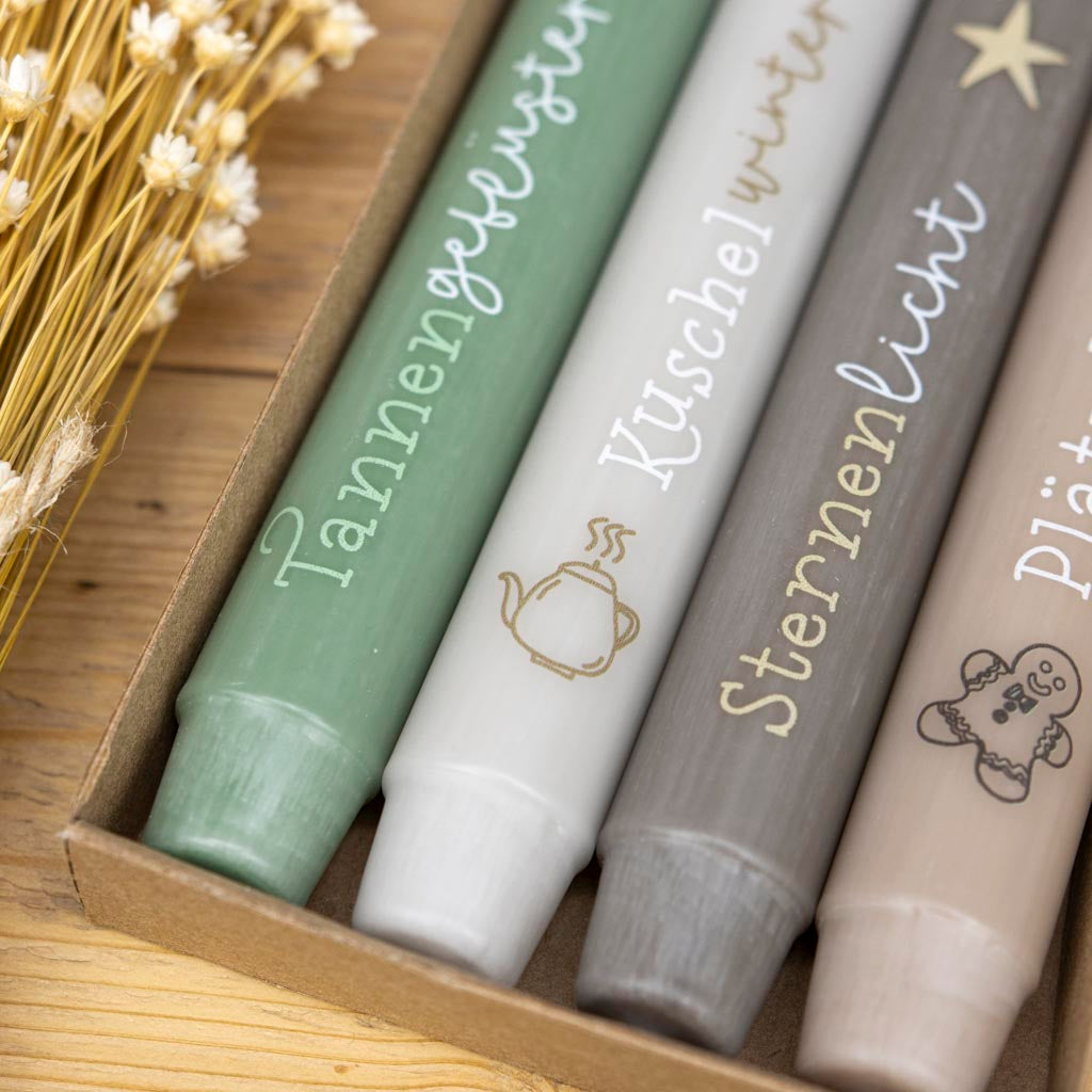 Vier Stabkerzen des Wintermomente-Sets mit winterlichen Motiven