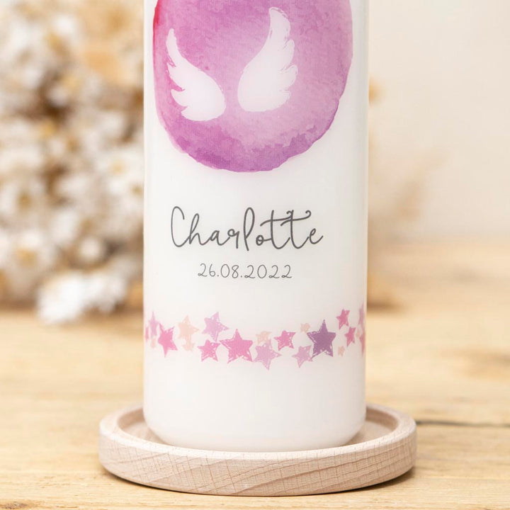 Taufkerze mit Sternenbordüre in Rosa und Lila auf dem Kerzenhalter Holz