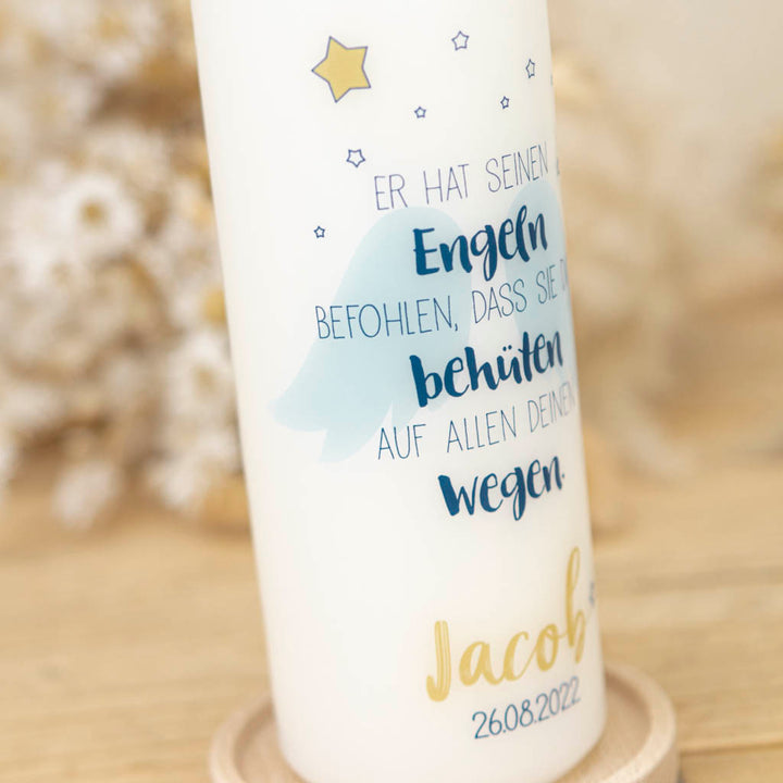Blaue Engelsflügel mit goldenen Sternen auf der Taufkerze