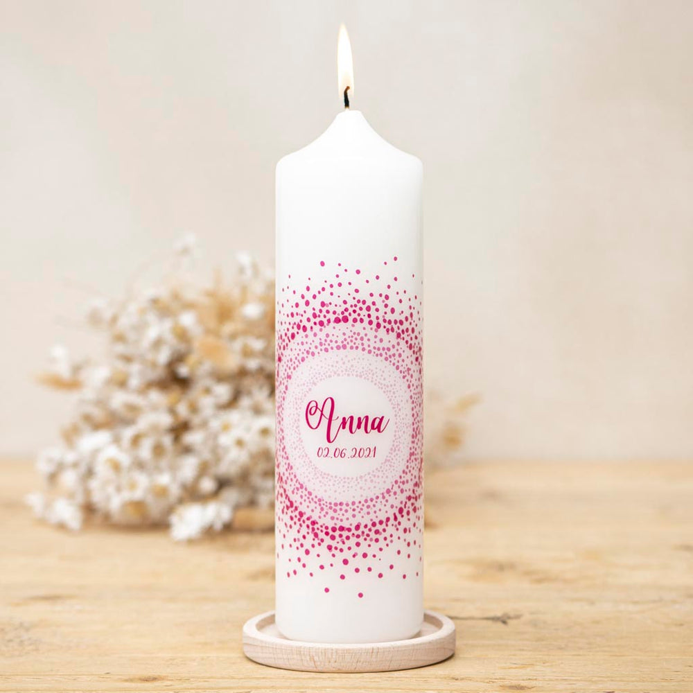 Taufkerze mit Punkte-Motiv in Pink auf einem Kerzenhalter aus Holz