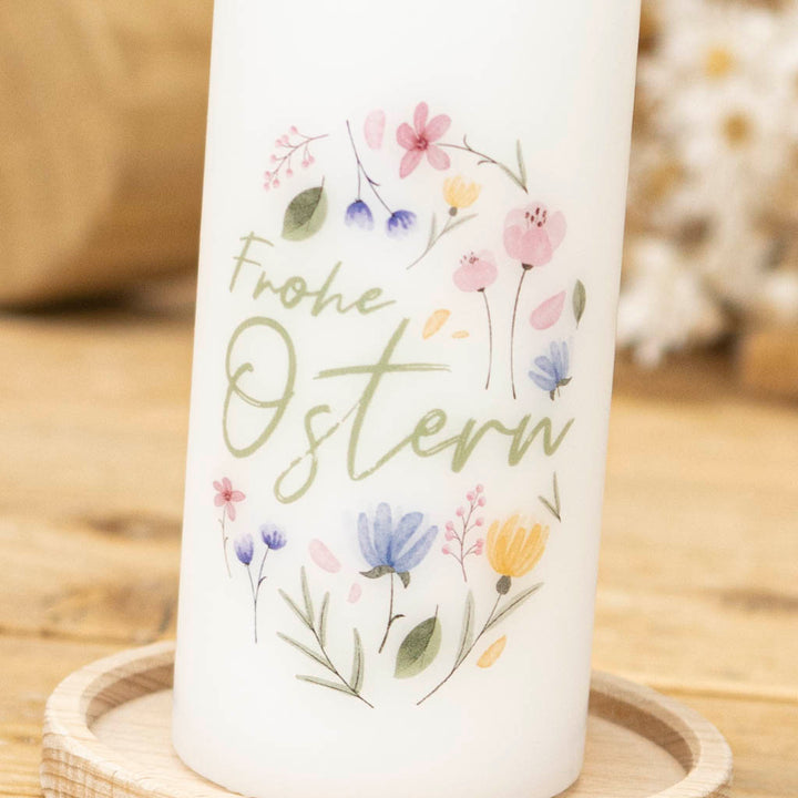 Osterkerze mit Blumen und dem Gruß Frohe Ostern